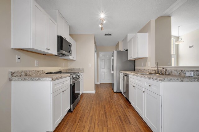 1790 Newman Ln, Tallahassee, FL 32312 - kitchen featuring appliances with stainless steel finishes, a sink, wood finished floors, white cabinets, and light countertops