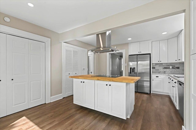 kitchen featuring island range hood, butcher block counters, appliances with stainless steel finishes, dark wood-type flooring, and a kitchen island