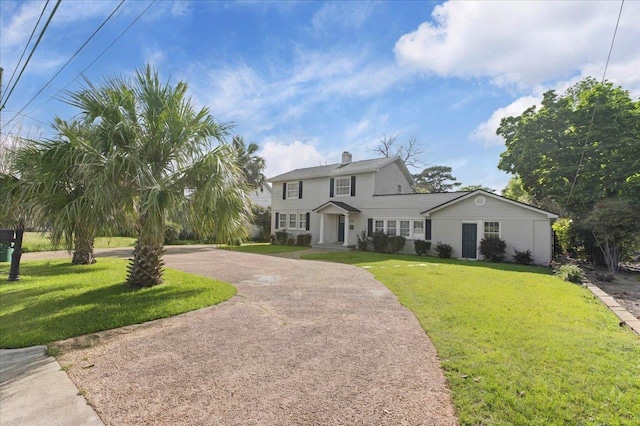 view of front of home featuring a chimney, a front lawn, and curved driveway