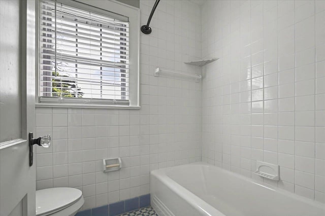 full bathroom with toilet, tile patterned floors, and tile walls