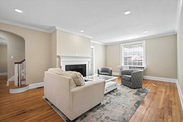 living area featuring recessed lighting, wood finished floors, arched walkways, a premium fireplace, and baseboards
