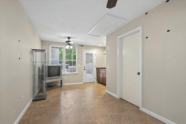 unfurnished living room with a ceiling fan and baseboards