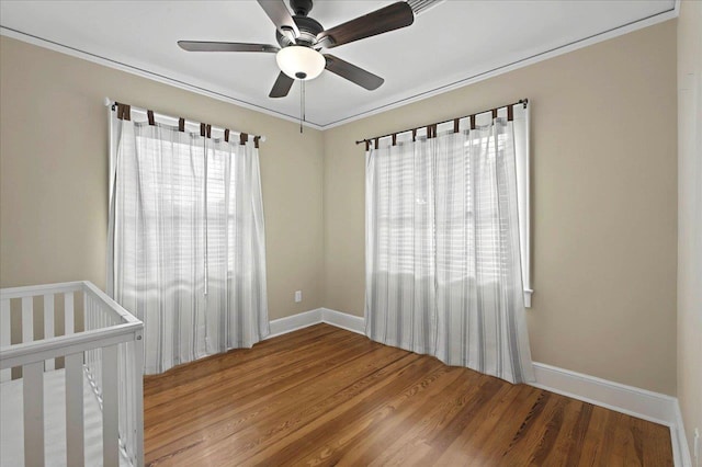 unfurnished bedroom featuring ceiling fan, baseboards, crown molding, and wood finished floors