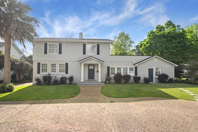 colonial inspired home with a chimney and a front yard