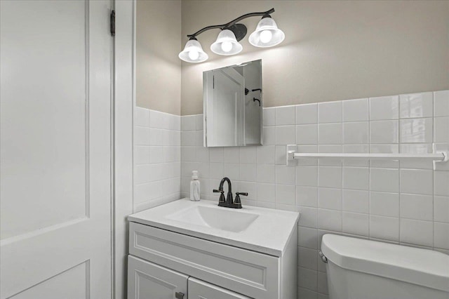 bathroom with tile walls, toilet, and vanity