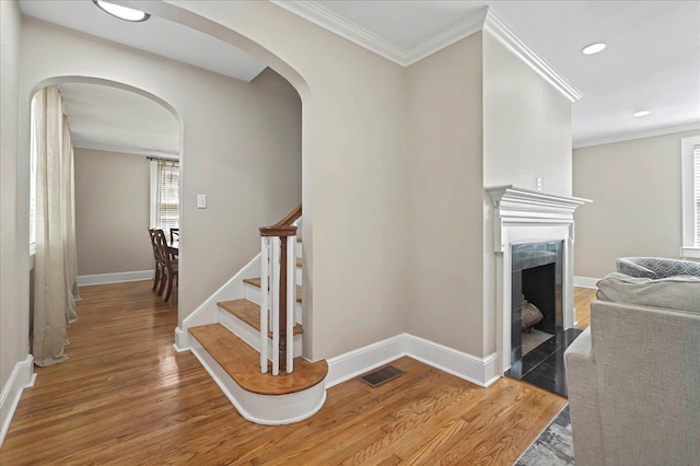 stairs with arched walkways, wood finished floors, visible vents, and baseboards