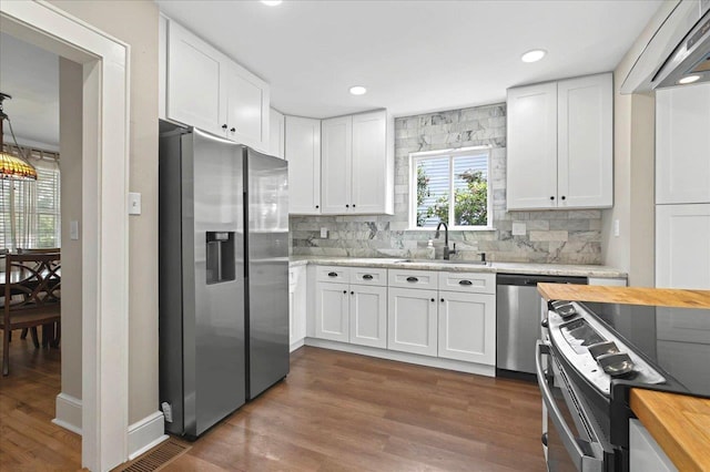 kitchen with butcher block counters, a sink, white cabinetry, and appliances with stainless steel finishes