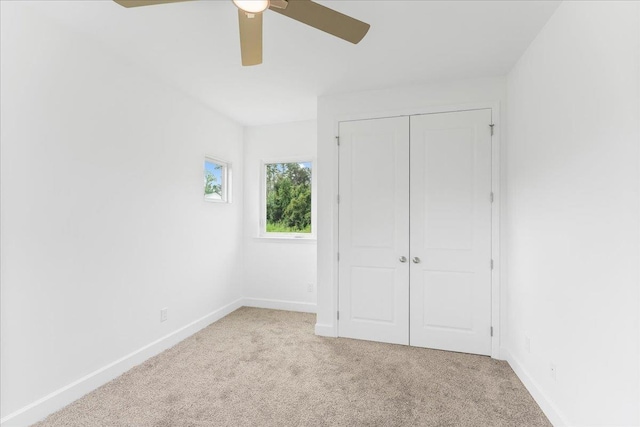 unfurnished bedroom featuring light carpet, a closet, and ceiling fan