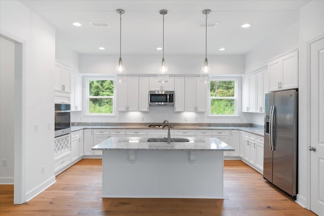 kitchen featuring white cabinetry, sink, an island with sink, and appliances with stainless steel finishes