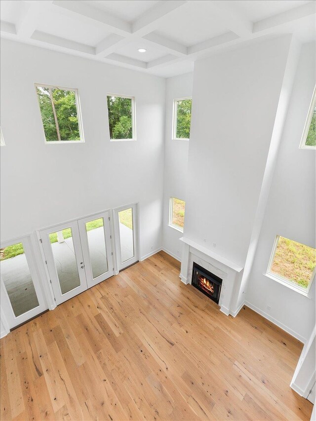 unfurnished living room with beamed ceiling, light hardwood / wood-style flooring, and coffered ceiling