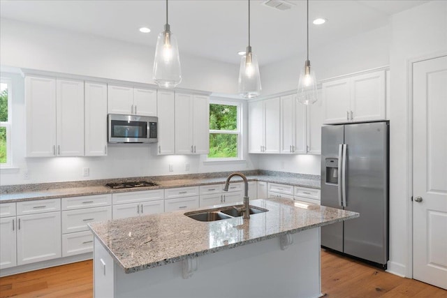 kitchen featuring white cabinetry, sink, stainless steel appliances, and decorative light fixtures