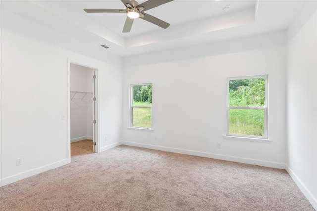 carpeted empty room with a tray ceiling and ceiling fan