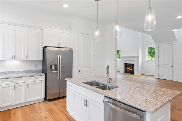 kitchen with a fireplace, sink, white cabinetry, and stainless steel appliances