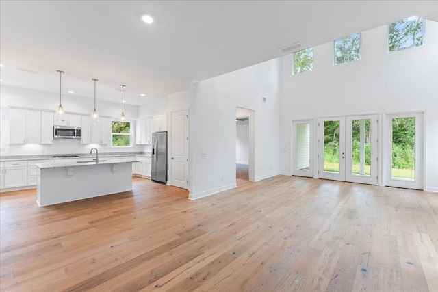 kitchen featuring white cabinets, a breakfast bar area, light stone countertops, an island with sink, and stainless steel appliances