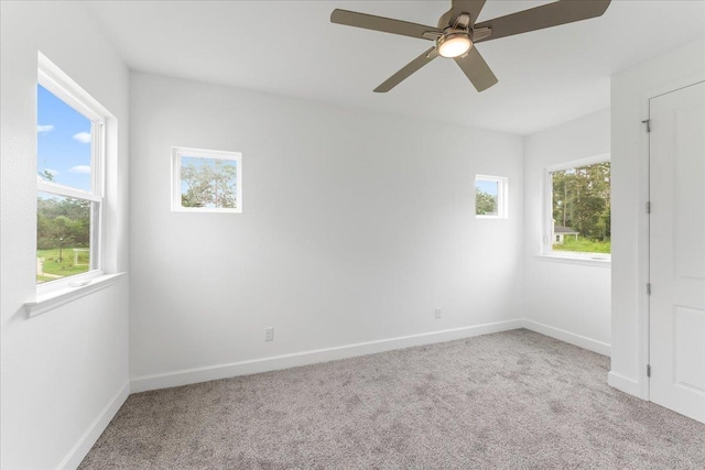 carpeted spare room featuring ceiling fan and a healthy amount of sunlight