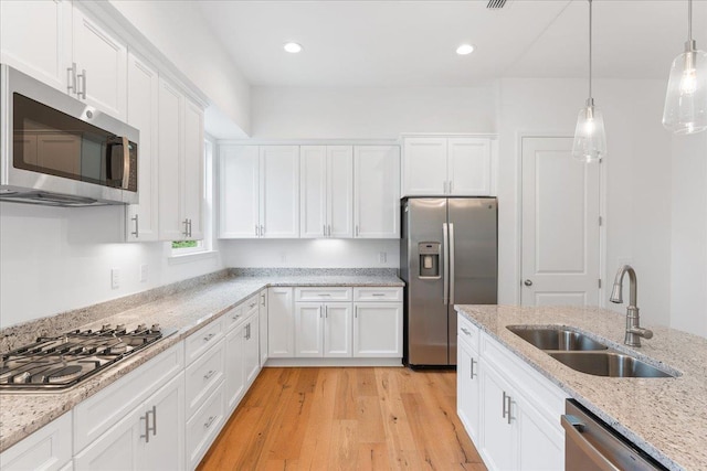 kitchen featuring white cabinetry, sink, light stone counters, and appliances with stainless steel finishes