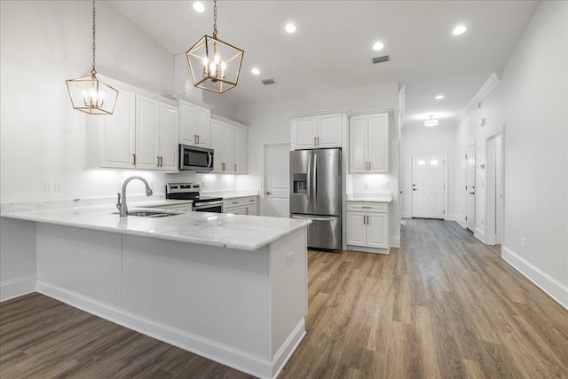 kitchen featuring appliances with stainless steel finishes, pendant lighting, sink, white cabinets, and kitchen peninsula