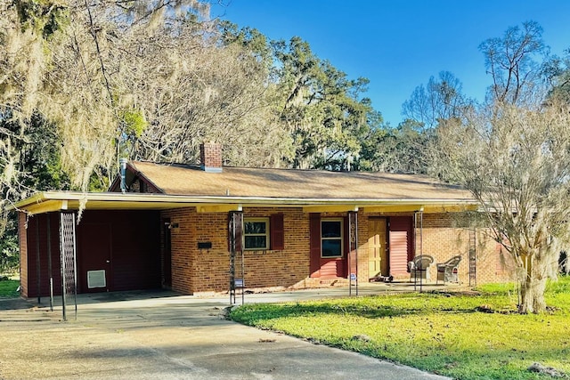 ranch-style home featuring brick siding, concrete driveway, a chimney, an attached carport, and a front yard