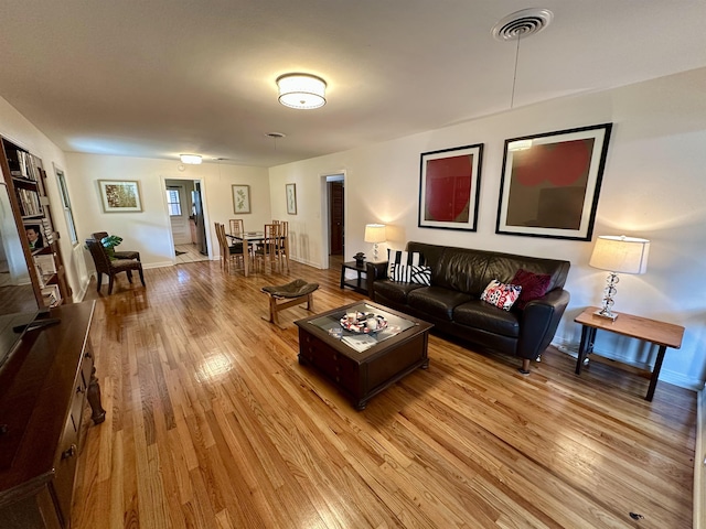 living area featuring light wood finished floors, baseboards, and visible vents