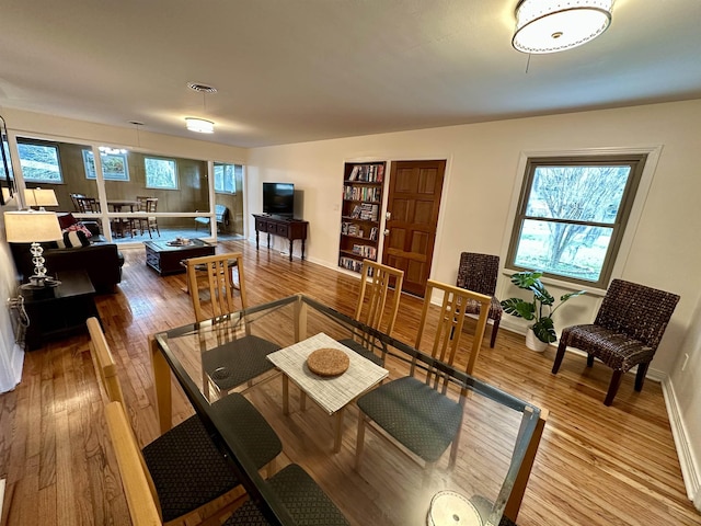 living room with a healthy amount of sunlight, visible vents, baseboards, and wood finished floors