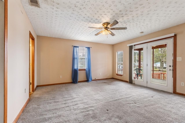 carpeted empty room featuring a textured ceiling, ceiling fan, and a wealth of natural light