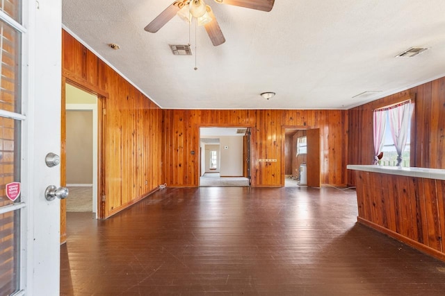 unfurnished living room featuring dark wood-type flooring, ceiling fan, and crown molding