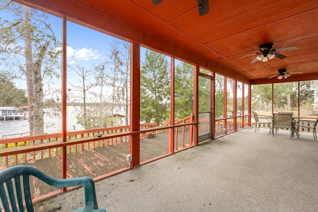 unfurnished sunroom with ceiling fan, wood ceiling, and a water view