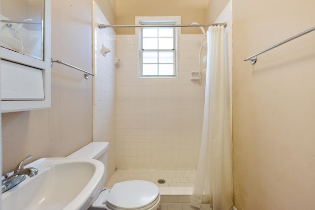 bathroom featuring toilet, a shower with shower curtain, and sink