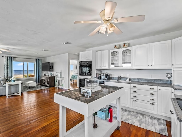 kitchen featuring sink, hardwood / wood-style flooring, ceiling fan, double oven, and white cabinetry