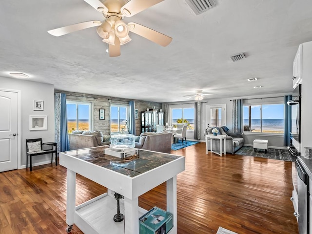 dining space with ceiling fan, a water view, and dark hardwood / wood-style floors