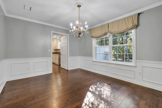 unfurnished dining area featuring crown molding, an inviting chandelier, dark wood finished floors, visible vents, and wainscoting
