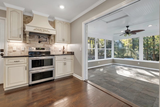 kitchen with tasteful backsplash, baseboards, dark wood finished floors, custom range hood, and range with two ovens