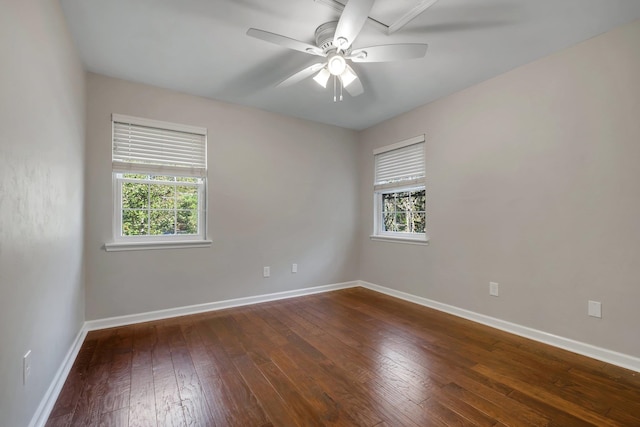 spare room featuring dark wood-style flooring, ceiling fan, baseboards, and a healthy amount of sunlight