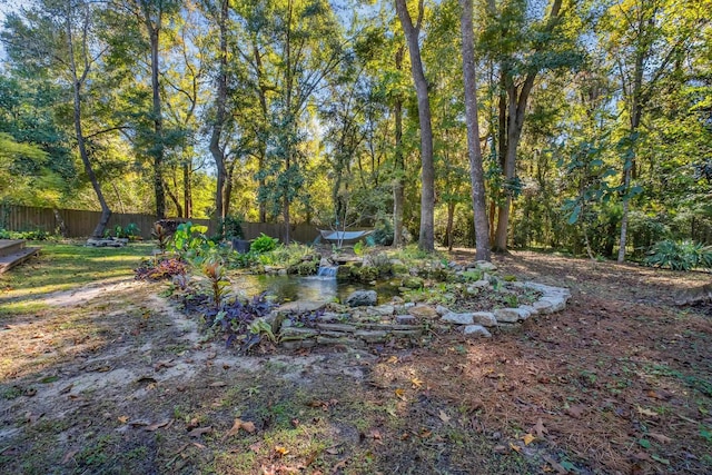 view of yard with a wooded view and fence