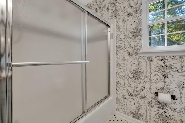 bathroom with bath / shower combo with glass door, baseboards, and wallpapered walls