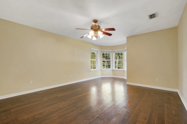 unfurnished room featuring dark wood-style flooring, visible vents, baseboards, and a ceiling fan