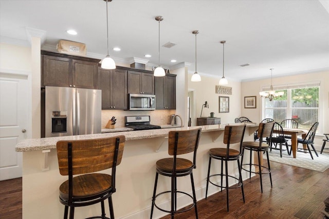 4516 Cavendish Ct, Tallahassee, FL 32309 - kitchen with appliances with stainless steel finishes, crown molding, dark brown cabinets, a chandelier, and dark wood-type flooring