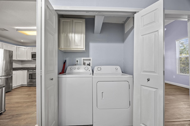 washroom featuring wood-type flooring, washer and clothes dryer, and cabinets