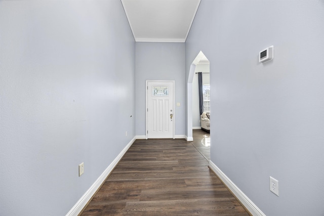 hallway with a towering ceiling, dark hardwood / wood-style flooring, and crown molding