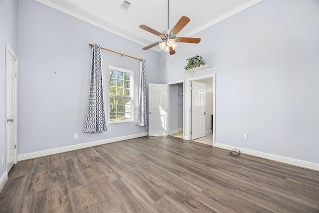 unfurnished bedroom featuring ceiling fan, a high ceiling, and hardwood / wood-style flooring