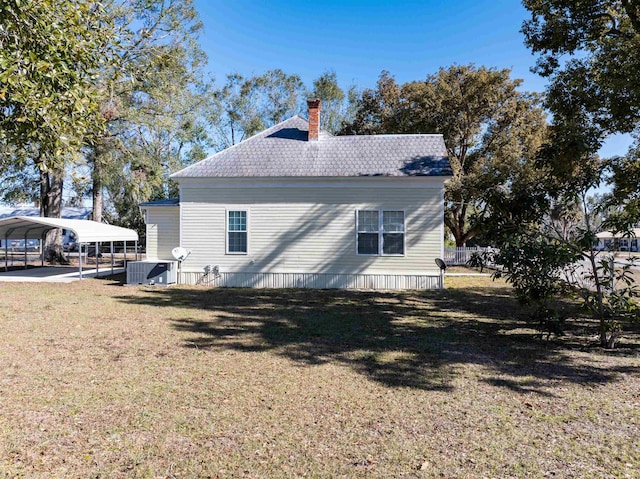 exterior space featuring a lawn, central AC, and a carport