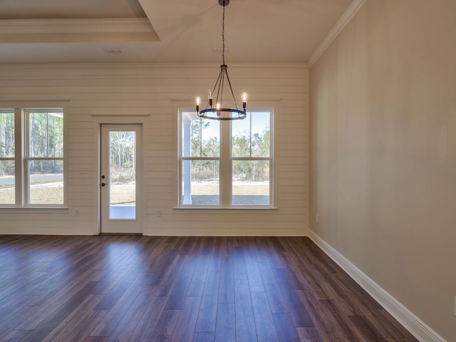 unfurnished dining area featuring ornamental molding, an inviting chandelier, dark wood-style flooring, and baseboards