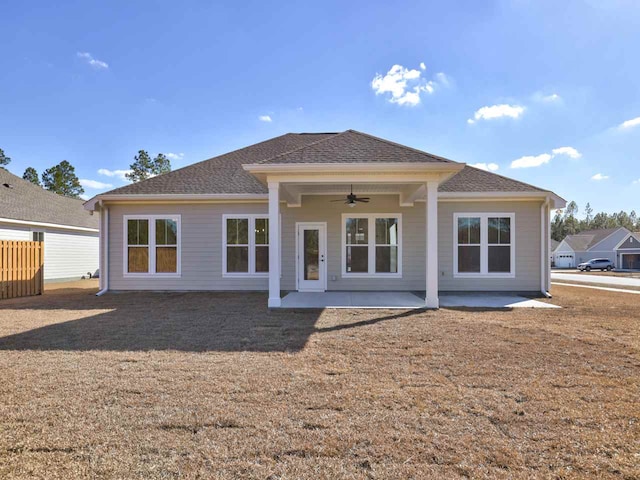 back of property with a patio, a ceiling fan, a yard, and roof with shingles