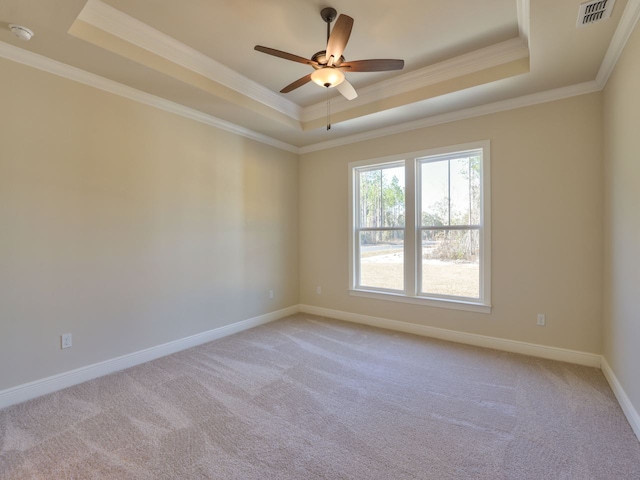 spare room featuring visible vents, a raised ceiling, light carpet, and ornamental molding