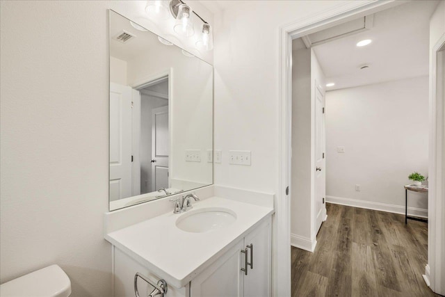 bathroom with hardwood / wood-style flooring, vanity, and toilet