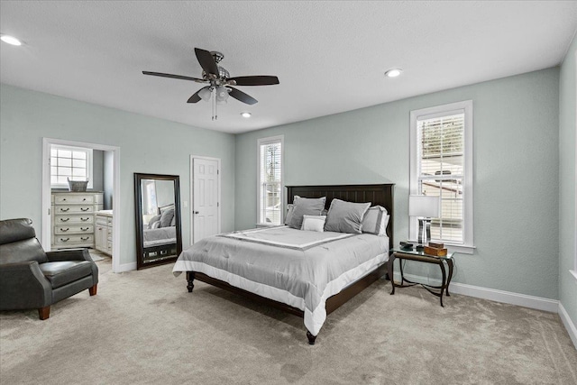 carpeted bedroom with ceiling fan, ensuite bath, and multiple windows