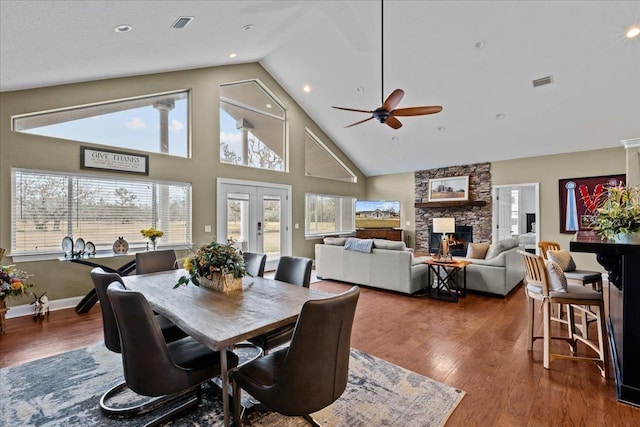 dining room with a fireplace, ceiling fan, dark hardwood / wood-style flooring, and high vaulted ceiling