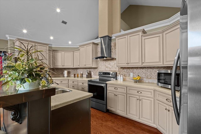 kitchen featuring wall chimney range hood, vaulted ceiling, dark hardwood / wood-style floors, appliances with stainless steel finishes, and cream cabinetry