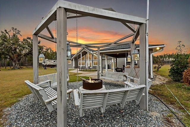 patio terrace at dusk featuring a fire pit and a lawn