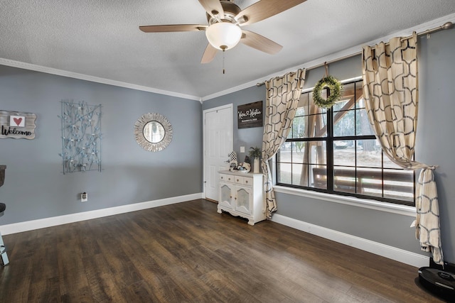 spare room featuring dark wood-type flooring, ceiling fan, ornamental molding, and a textured ceiling